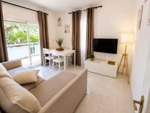a living room with a couch and a tv and a table at Apartamentos Baymar Playa de Aro in Platja d'Aro