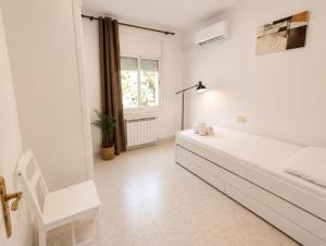 a white bedroom with a bed and a window at Apartamentos Baymar Playa de Aro in Platja d'Aro