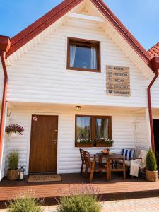 a white house with a wooden table in front of it at Bursztynowe Domki in Sarbinowo
