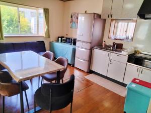 a kitchen with a table and chairs and a refrigerator at Sakura Inn in Chiba
