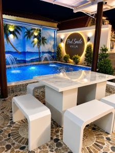 a table and benches in front of a swimming pool at Pool Smile Villa in Bangsaen