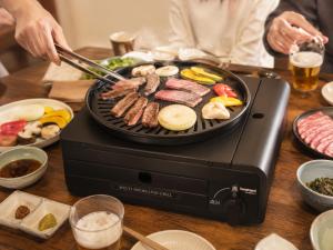 a person cooking meat and vegetables on a grill at Yuimaru EAST - 最大18名貸切OK in Kanazawa