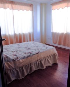 a bedroom with a bed and two windows at Alojamiento Primer Piso Confort Riobamba in Riobamba