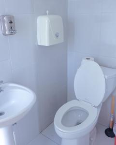 a white bathroom with a toilet and a sink at Alojamiento Primer Piso Confort Riobamba in Riobamba