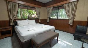 a bedroom with a bed and a chair and windows at Banna Resort in Ban Khlong Kadon (1) +35 photos