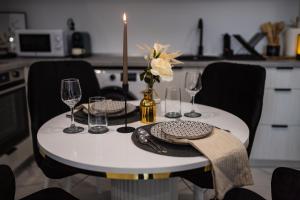 a white table with a candle and wine glasses on it at Olive Apartment Cosmopolis in Tunari
