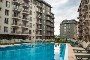 a swimming pool in front of some apartment buildings at Olive Apartment Cosmopolis in Tunari