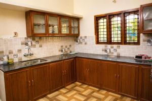 a kitchen with wooden cabinets and a sink at Misty Leaf in Thekkady