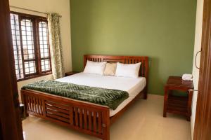 a bedroom with a wooden bed with a green wall at Misty Leaf in Thekkady