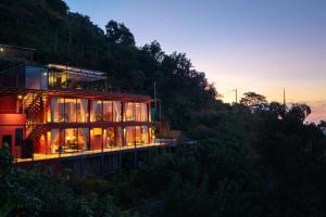a house on the side of a hill at dusk at Villa Cavo - Beneath the Misty Peaks in Haputale