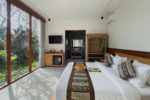 a bedroom with a bed and a large window at Santosha Place in Ubud