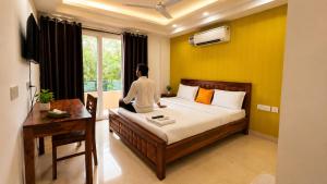 a man sitting on a bed in a room at Lime Tree Hotel Golf Course Extension Nearby Grand Hyatt Gurgaon in Gurgaon +11 photos