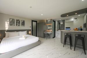 a bedroom with a white bed and a kitchen at Root and Rise Cabins in Tabanan