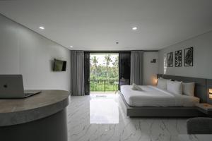 a bedroom with a bed and a desk with a laptop at Root and Rise Cabins in Tabanan