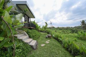 a house with a walkway leading to a yard at Root and Rise Cabins in Tabanan