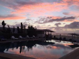 a swimming pool with chairs and a sunset in the background at Auberge Oualidia Dream in Oualidia