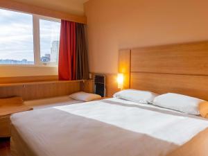 a bedroom with a large white bed and a window at ibis Novo Hamburgo in Novo Hamburgo +68 photos