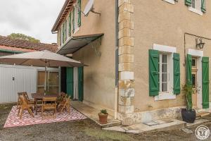 a table with an umbrella next to a building at L'ecole à l'ancienne in Aulon