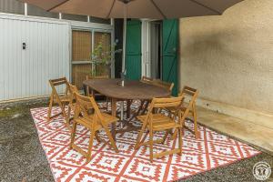a wooden table with chairs and an umbrella on a rug at L'ecole à l'ancienne in Aulon