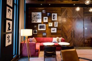 a living room with a red couch and a table at Cambria Hotel Boston Somerville in Somerville