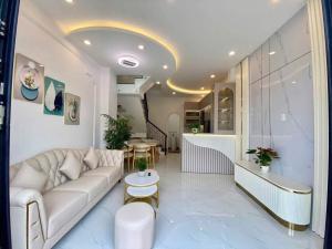 a living room with a white couch and a staircase at Sunrak House in Ðạo Thành