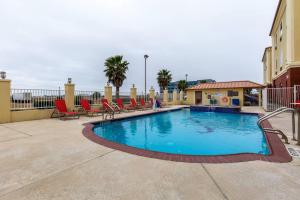 a swimming pool with lounge chairs and a swimming pool at Comfort Suites Galveston Cruise Port Area - Beachside in Galveston