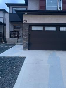 a garage door on a house with a driveway at Lakeview 2Bedroom Walkout Suite with Trail View in Winnipeg
