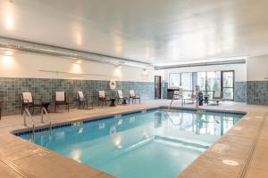 a swimming pool with chairs and a table and a person sitting at Cambria Hotel & Suites Plymouth in Plymouth