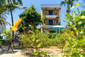 a building in front of a garden with tables and chairs at Calm House 4 Hoi An in Hoi An