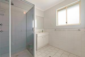 a white bathroom with a shower and a glass door at Tahren Beach Getaway in Middleton +15 photos
