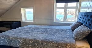 a bedroom with a blue bed with two windows at Boat Included, Waterfront Villa, Near Bergen in Lindås