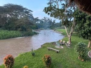 a river with a group of benches next to a tree at At the river campsite in Kihihi