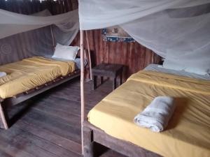 a couple of beds in a room with a canopy at At the river campsite in Kihihi
