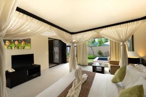 a bedroom with a bed with curtains and a television at The Yubi Boutique Villas Seminyak in Seminyak