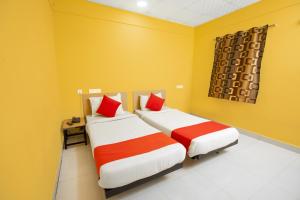 two beds in a room with yellow walls and red pillows at Pondy VMB Residency Starlight Hotels in Pondicherry