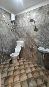 a bathroom with a shower and a toilet and a sink at Vandalur Stay's Inn in Vandalūr