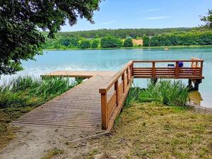 a wooden dock with a bench on a lake at Domek nad morzem Wisełka in Wisełka