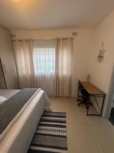 a bedroom with a bed and a desk and a window at Crescent Bud in Durban