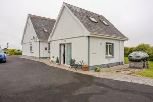 a white house with a car parked in front of it at Lorna's Apartment Self Catering Holiday Home in Milltown Malbay