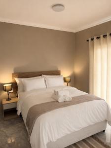 a bedroom with a large white bed with two stuffed animals on it at Jets Stay Property in Cape Town