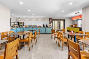 a restaurant with tables and chairs and a kitchen at Country Inn & Suites by Radisson Kenosha - Pleasant Prairie in Kenosha