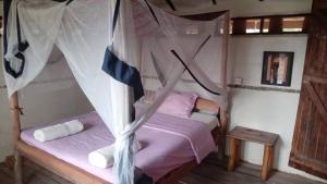 a bedroom with a bed with a mosquito net at At the river campsite in Kihihi