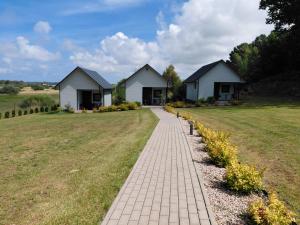 a brick path in front of two white houses at Wichrowa Skarpa in Rusinowo