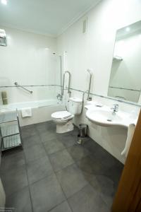 a bathroom with a sink and a toilet and a mirror at Hotel El Roble in Cervera de Pisuerga