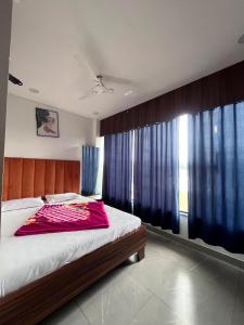 a bedroom with a large bed with blue curtains at Jalsa hotel in Raipura