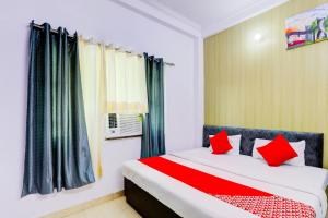 a bedroom with a bed with red pillows at Hotel O Raama in Lucknow