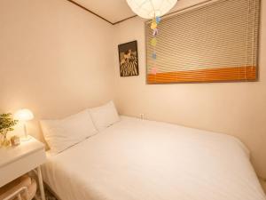 a small bedroom with a white bed and a window at Maison de Jann in Seoul
