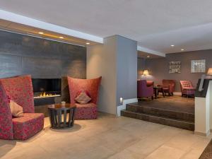 a lobby with chairs and a fireplace and a table at Pullman Munich in Munich