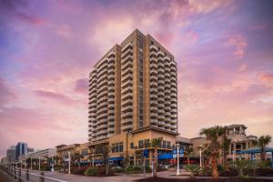 a tall building with palm trees in front of it at Hilton Virginia Beach Oceanfront in Virginia Beach