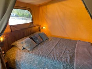 a bed in a tent with two pillows on it at Camping Les Chagnelles in Le Perrier